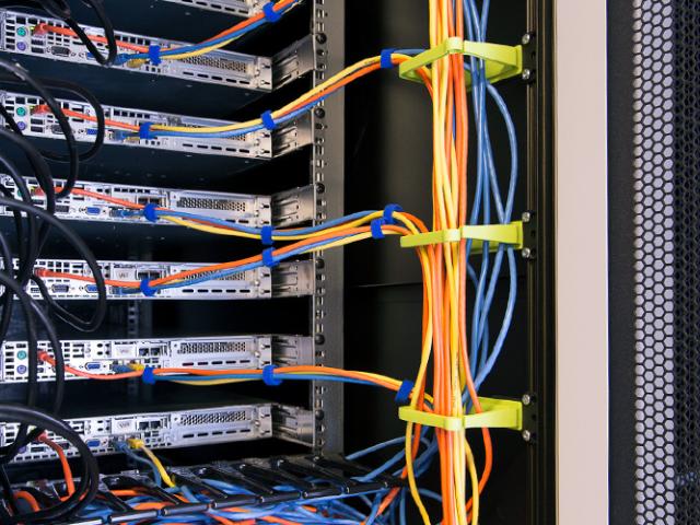 Interior view of an Enoc server rack with mounted cable management, featuring color-coded network cables in blue, orange, and black, organized with Velcro straps and connected to networking equipment