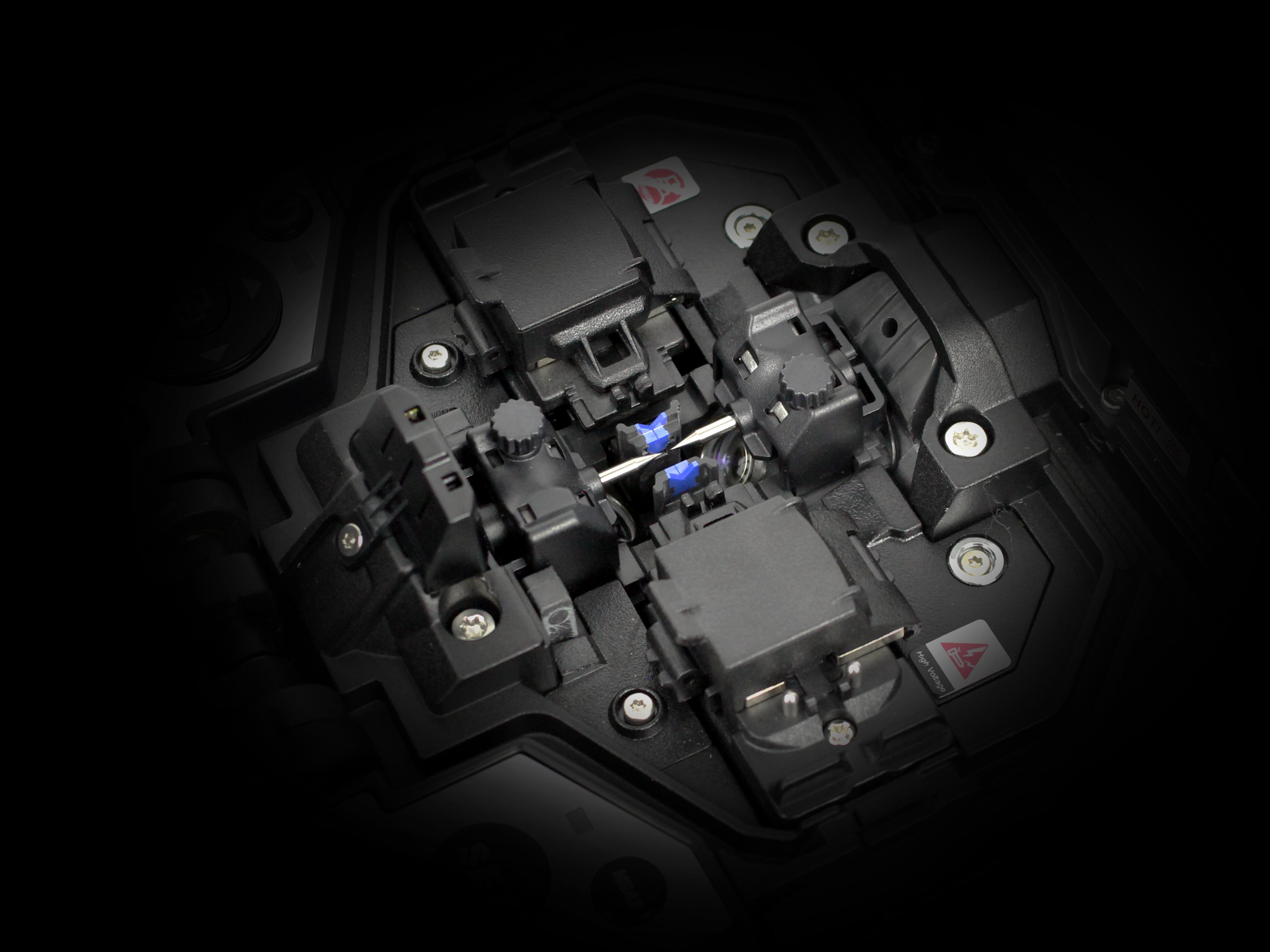 Close-up view of a fiber optic fusion splicer aligning and fusing two optical fibers with a visible blue arc.